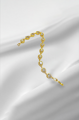 Gold bracelet with heart-shaped stones on a white fabric background