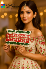 A beautiful girl holding a white clutch bag with green and red ribbon work and pearl-like embellishments, displayed against a marble background.