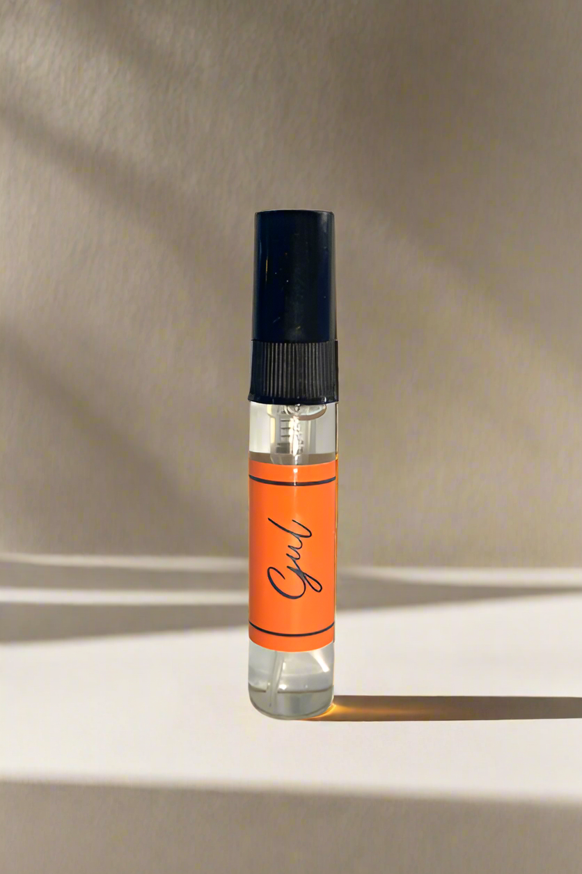 Small perfume bottle with an orange label on a gray background