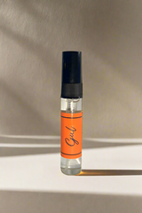 Small perfume bottle with an orange label on a gray background