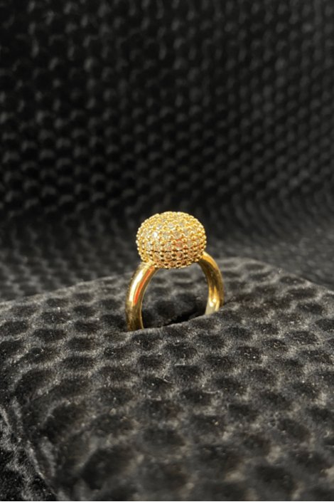 Gold ring with a textured design on a black textured surface