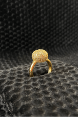 Gold ring with a textured design on a black textured surface