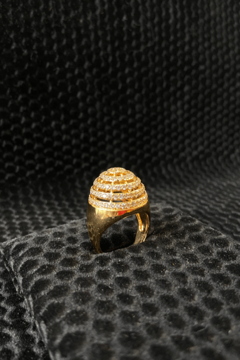 Gold ring with intricate design on a black textured surface