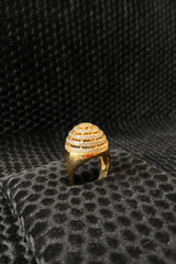 Gold ring with intricate design on a black textured surface
