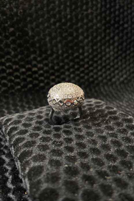 Silver ring with gemstones on a textured black surface