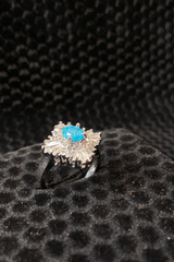 Silver ring with a blue gemstone on a black textured surface