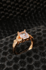 Rose gold ring with a large diamond on a black textured background