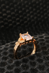 Rose gold ring with a diamond on a black textured background