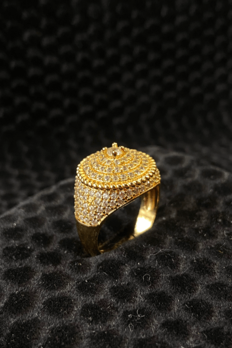 Gold ring with intricate design on a black textured background