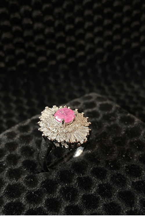 Silver ring with a pink gemstone on a black textured background