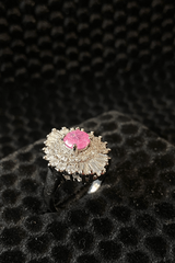 Silver ring with a pink gemstone on a black textured background