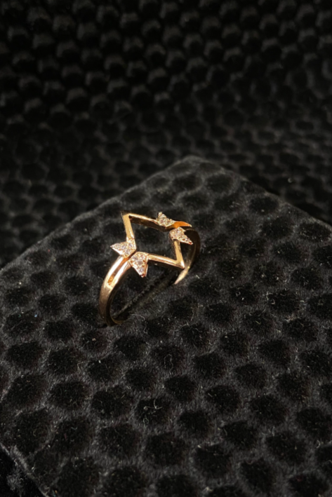 Gold ring with star design on a black textured surface