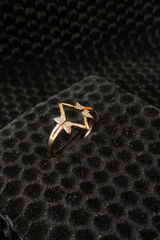 Gold ring with star design on a black textured surface