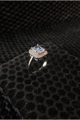 Silver ring with a large central gemstone on a textured black surface
