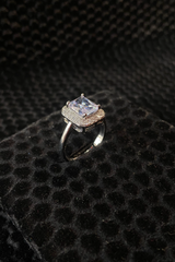 Silver ring with a large central gemstone on a textured black surface