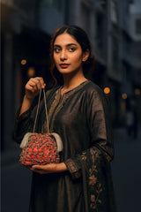 Woman holding a red handbag with intricate patterns against a blurred background