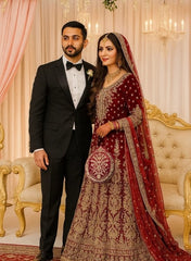 Man in a black tuxedo and woman in a red and gold traditional outfit standing in an ornate room holding a Elegant Drop Shape Clutch Bag.