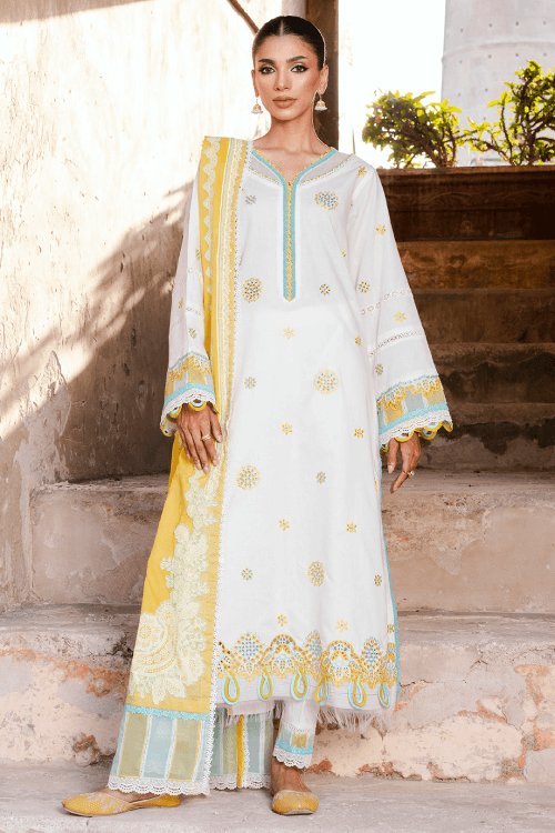 Woman wearing a traditional outfit with white and yellow patterns, standing outdoors.
