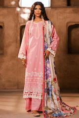Woman wearing a traditional pink and floral outfit against a textured wall.