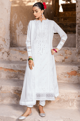 Woman in a white traditional outfit standing on stone steps.