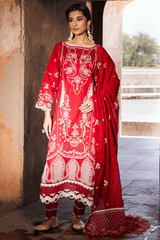 Woman wearing a red and white embroidered traditional outfit in an outdoor setting.