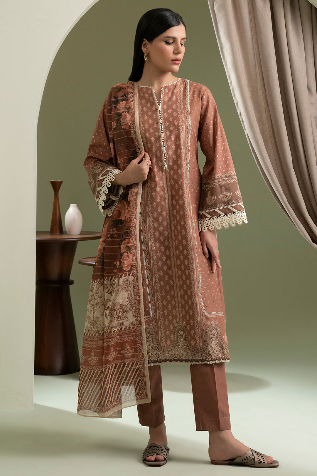 Woman wearing a patterned outfit standing in a room with a neutral color scheme.