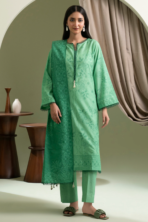 Woman wearing a green traditional outfit standing in a room with decorative elements.