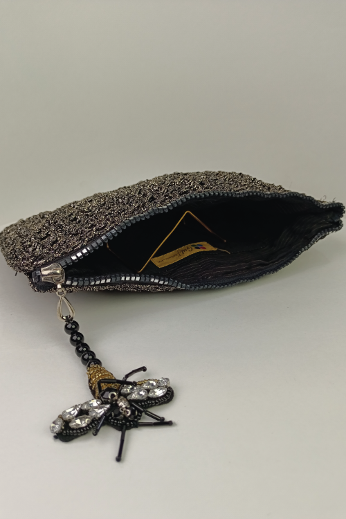 A black and silver fabric clutch bag with a floral pattern, displayed on a stand.