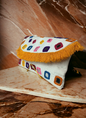 A white multicolor mirror worked clutch bag with a vibrant and colorful design, placed on a marble surface.